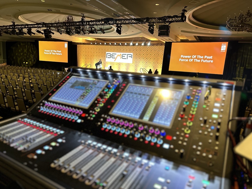 AFPC live event production control position overlooking a ballroom event with stage, projection, audio, lighting, and audience seating